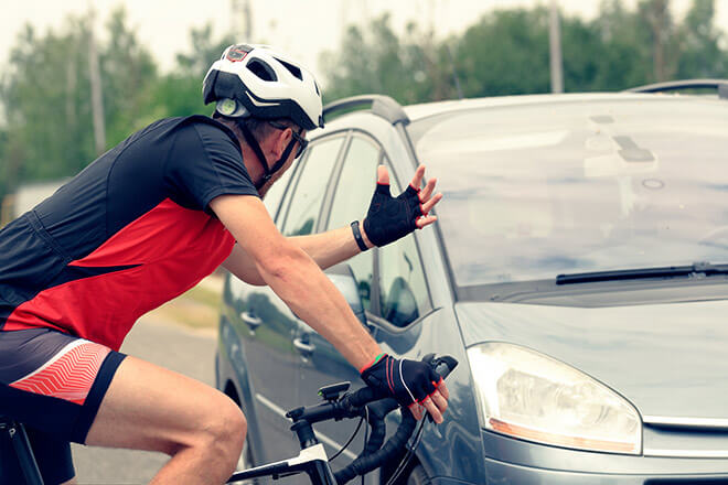 Near miss accident : a cyclist is stopped near a car after a harsh braking. 